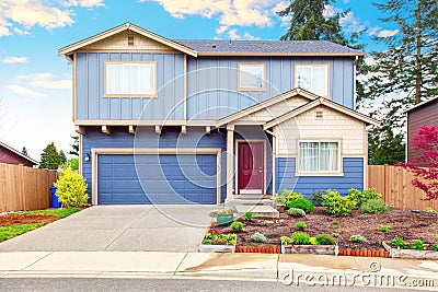 Nice curb appeal of blue house with front garden and garage Stock Photo