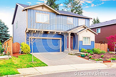 Nice curb appeal of blue house with front garden and garage with driveway Stock Photo