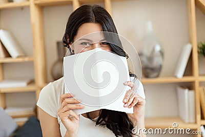 Nice female smile. Pretty woman covered her face with a book. Stock Photo