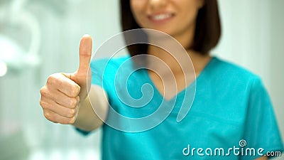 Nice female stomatologist smiling at camera, showing thumbs-up, health care Stock Photo