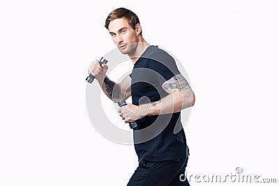 nice guy with dumbbells in a black t-shirt and trousers goes in for sports side view Stock Photo