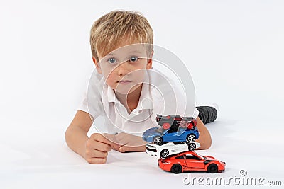 Nice looking very young boy lying with a pile of car toys and having a sincere neutral and proud look in his face Stock Photo