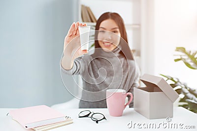 Nice picture of attractive girl sitting at the table and showing the beauty product to the camera. It is hand cream Stock Photo