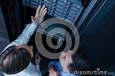 Nice professional technician pointing at the hard drives Stock Photo