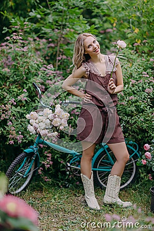 Nice smiling young woman with peony flower in summer garden Stock Photo