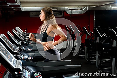 Nice sporty girl running on a treadmill at the gym Stock Photo