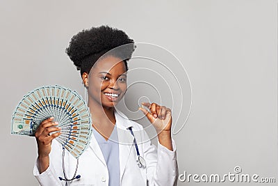 Nice successful african american woman doctor smiles and holds fan of money one hundred dollar against white background Stock Photo