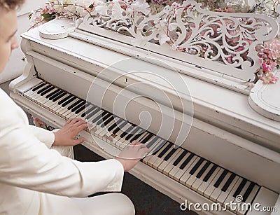 Close up of teenager arms with old white grand piano. person in white clothes plays music. Stock Photo