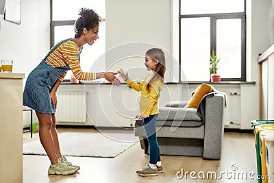 Nice to meet you. African american woman baby sitter get acquainted with caucasian cute little girl. They are standing Stock Photo