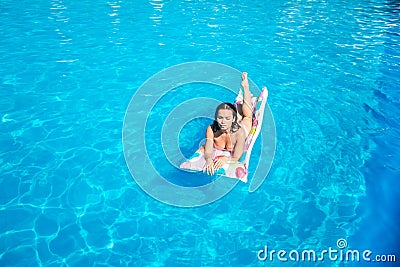 Nice and well-built girl is lying on air mattress and getting some tan from sun. She is serious and concentrated. Girl Stock Photo