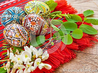 Nicely hand decorated romanian orthodox easter eggs with traditional motifs on a red cloth with acacia flowers aside Stock Photo