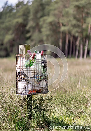 A metal litter bin full with rubbish on a wooden post in the countryside Editorial Stock Photo