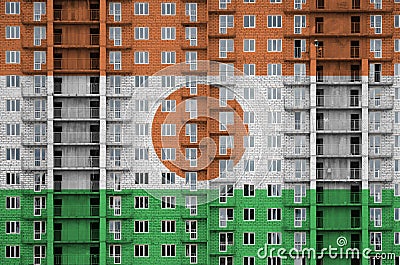 Niger flag depicted in paint colors on multi-storey residental building under construction. Textured banner on brick wall Stock Photo