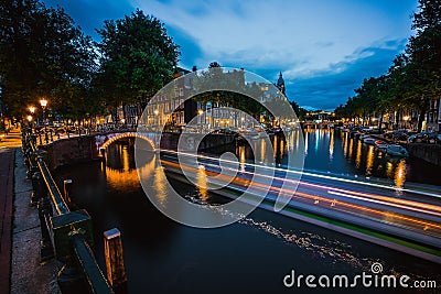 Night in Amsterdam. Lights trails and illuminated bridges on city canal at twilight. Holland, Netherlands. Long exposure Stock Photo