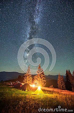 Night camping in mountains under starry sky with Milky way. Stock Photo