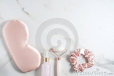 Night care oil for face, sleeping eye mask, hair elastic and facial massage roller on marble background. nighttime Stock Photo