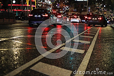 Night city. Asphalt in focus is visible its technical equipment. Asphalt after rain wet Editorial Stock Photo