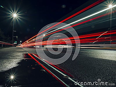 Night city scene with puddle by a road and car light trail. Dark night sky. Town traffic Stock Photo