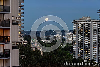 Night city view with full yellow moon raising over Stock Photo