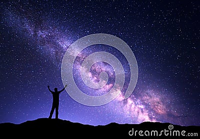 Night colorful landscape with purple Milky Way and silhouette of a standing sporty man with raised up arms on the mountain Stock Photo