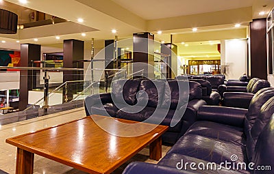 Night interior of the resort European hotel, illuminated staircase with transparent railing, leather sofas with tables for Editorial Stock Photo