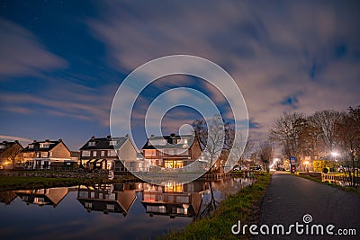 Night landscape with starry sky in the Dutch village of Streefkerk. Houses with bright light reflecting in the shine of the water Stock Photo