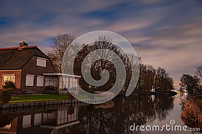 Night landscape with starry sky in the Dutch village of Streefkerk. Houses with bright light reflecting in the shine of the water Stock Photo