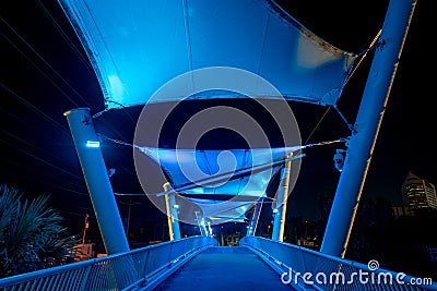 Night photo of a neon blue pedestrian walkway over a road Editorial Stock Photo