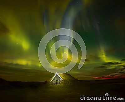 Night photo. Northern lights and a small house in the land overgrown with grass. Iceland. Stock Photo