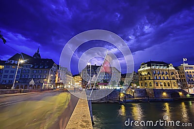 Night scene plus lightning in the sky of Basel on Mittlere Brucke stone bridge with Eisengasse road ahead, Switzerland Editorial Stock Photo