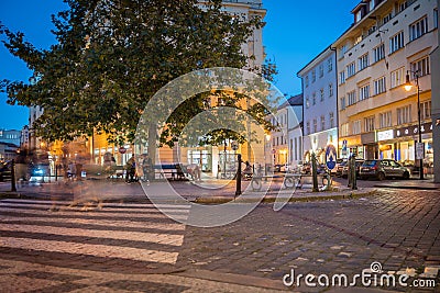Night scene street corner with tall tree and pedestrian crossing, people blurred in log exposure Editorial Stock Photo