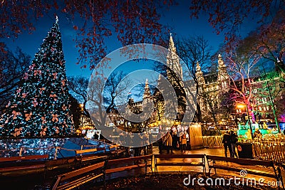 Night shot of Christmas markets at Rathausplatz, lighted ornate tree with colorful lights, town hall in the background Editorial Stock Photo