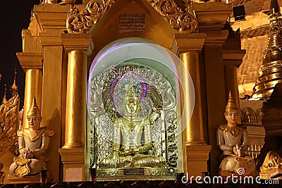 Night shot of stucco buddha statue decorated in golden be enshrined inside the arch at Shwedagon Pagoda, Yangon Stock Photo