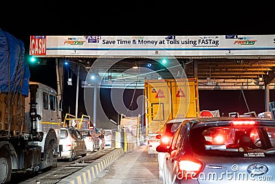 Night shot of vehicles waiting at NHAI toll booth while a large white headboard talks about FASTag and Paytm Editorial Stock Photo