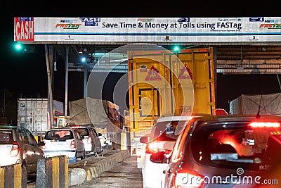 Night shot of vehicles waiting at NHAI toll booth while a large white headboard talks about FASTag and Paytm Editorial Stock Photo