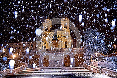Night snowfall on empty Spanish square and steps in Rome with church Trinita di Monti in background, Italy. Piazza di Spagna Stock Photo