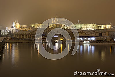 Night snowy Prague Lesser Town with gothic Castle, Bridge Tower and St. Nicholas' Cathedral and Charles Bridge Editorial Stock Photo