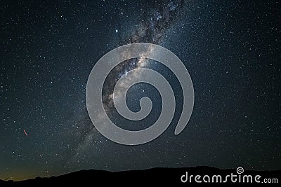 The Milky Way galaxy rising above mountains against a dark starry sky Stock Photo