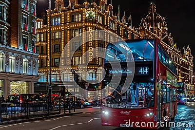 Night view with red double decker bus on moving in front of Harrods Editorial Stock Photo