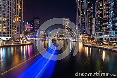 Night view to Dubai Marina panorama, reveals Pier 7, skyscrapers, speed boat light trails and beautiful bridge. Editorial Stock Photo