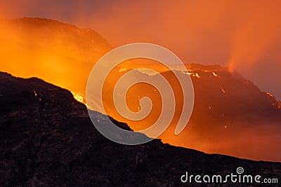 Night volcanic eruption. Fresh hot lava, flames and poisonous gases going out from the crater Stock Photo
