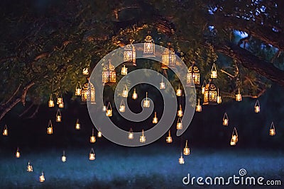 Night wedding ceremony with a lot vintage lamps and candles on big tree Stock Photo