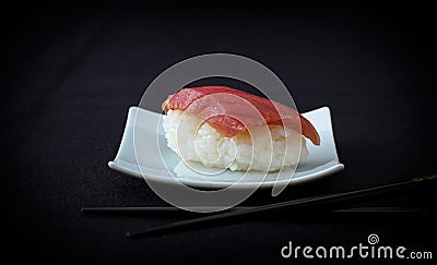 Nigiri tuna sushi with chopstick on black Stock Photo