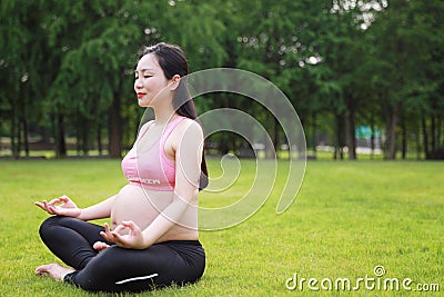 Asian Eastern Chinese young pretty pregnant girl woman do yoga sit in meditation, do lotus gesture of yoga closed-eyes over sunset Stock Photo