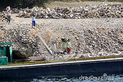 Egyptian workers load stones by hand on a barge on the Nile River Editorial Stock Photo
