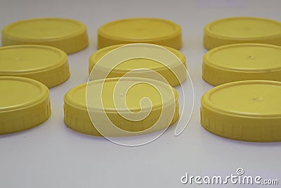 Nine plastic yellow round lid jars on a white background Stock Photo