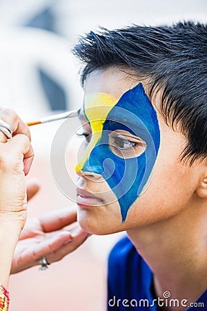 Nine year boy handsome child young having his face painted for fun at a birthday party Stock Photo