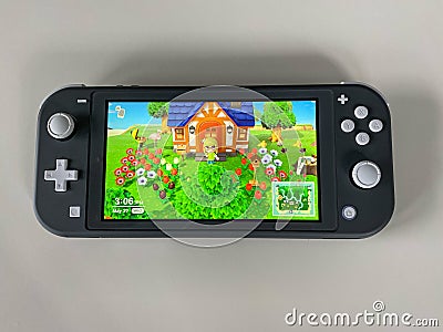 A Nintendo Switch Lite with the game Animal Crossing New Horizons running on it Editorial Stock Photo