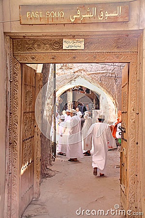 NIZWA, OMAN - FEBRUARY 3, 2012: Entrance of the East Souq in Nizwa Old Town with Omani men traditionally dressed Editorial Stock Photo