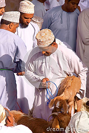 NIZWA, OMAN - FEBRUARY 3, 2012: Omani men traditionally dressed attending the Goat Market in Nizwa Editorial Stock Photo